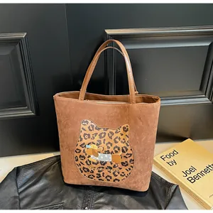 Detail of camel tote bag featuring leopard print cat patch and cartoon puppy embroidery