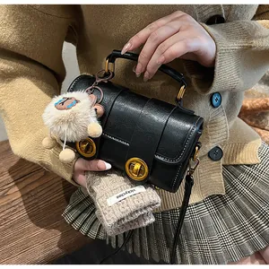 Détail du sac polochon rétro noir avec verrous dorés et breloque en peluche blanche
