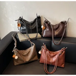 Detail of soft leather bucket bags with contrast stitching and baseball charm accessories