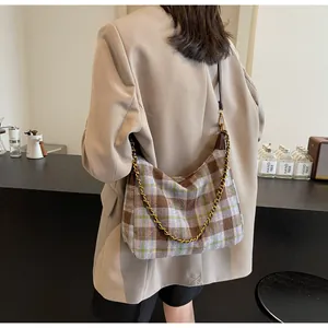 Détail d'un sac sous le bras à carreaux vintage avec chaîne dorée sur blazer beige