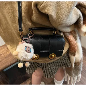Détail du sac polochon en cuir noir avec boucles dorées et pendentif mouton blanc