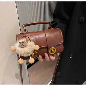 Détail du sac polochon marron rétro avec boucle dorée et charm mouton pelucheux
