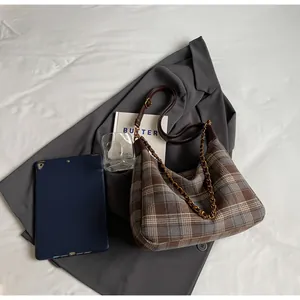 Détail de la texture à carreaux marron et de la chaîne dorée du sac de bureau chic