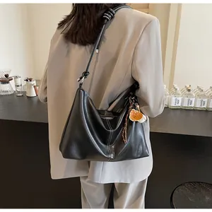 Detail of black leather bucket bag with white stitching and cute woven charm on model