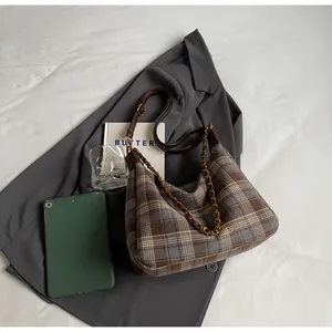 Détail du tissu à carreaux vintage et de la bandoulière en cuir d'un sac hobo croissant