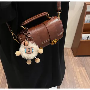 Vue détaillée d'un sac polochon marron vintage avec un charme de poupée en peluche porté épaule