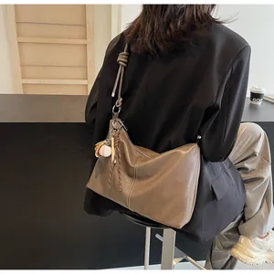 Detail view of khaki brown bucket bag with white stitching and baseball charm