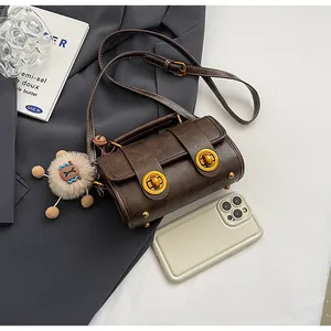 Détail du sac oreiller en cuir marron vintage avec boucles dorées et breloque en peluche