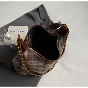 Détail du sac seau à carreaux vintage avec bandoulière chaîne dorée et fermeture