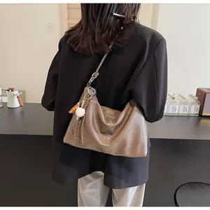 Detail of vintage brown leather bucket bag with baseball charm and tassel on a casual strap
