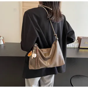 Detail of coffee brown leather tote bag featuring a baseball charm and knotted strap detail