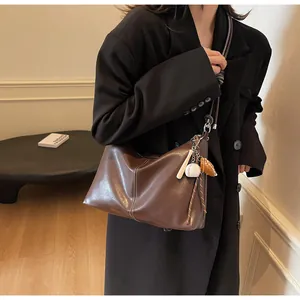 Detail view of large brown leather bucket bag with white stitching and baseball charms