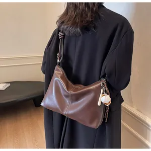 Detail view of large dark brown leather bucket bag with retro baseball pendant charm