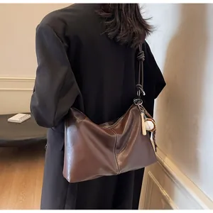 Detail of dark brown leather bucket bag featuring white contrast stitching and baseball charm