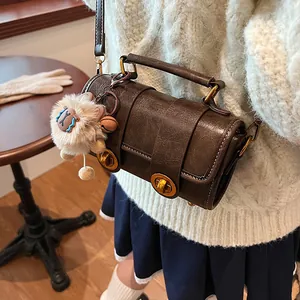 Sac oreiller rétro en cuir marron avec fermoirs dorés et breloque agneau sur le mannequin