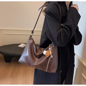 Detail of dark brown bucket bag with white contrast stitching and knotted shoulder strap