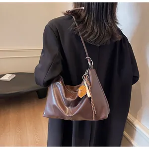 Detail of vintage brown bucket bag with contrast stitching and fruit charm accessory