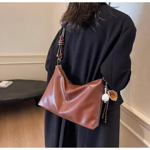 Brown leather bucket bag detail with woven knotted strap and cute sports charm pendant