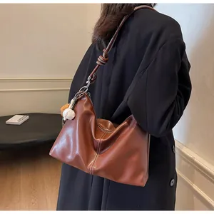 Detail of soft brown leather hobo bag with white stitching and rope knot strap