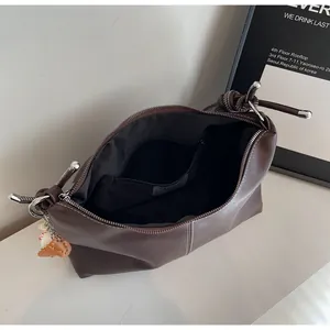 Internal view of brown bucket bag featuring black lining and functional zip pocket