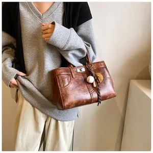Detail of vintage brown tote bag with metal twist lock and baseball themed bag charm