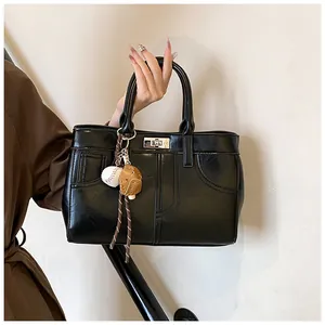 Detail of black faux leather tote with silver twist-lock and baseball themed charms