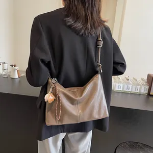 Brown leather bucket bag with knotted strap and woven pendant for daily commute