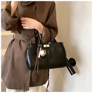 Close-up of black leather handbag featuring a silver twist lock and baseball charm detail