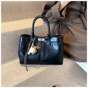 Detail of black faux leather handbag with silver twist lock and baseball charm decoration