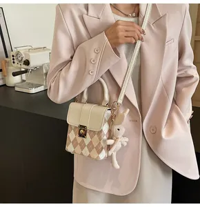 Detail showing pink quilted handbag with gold clasp, handle, and cute plush rabbit charm