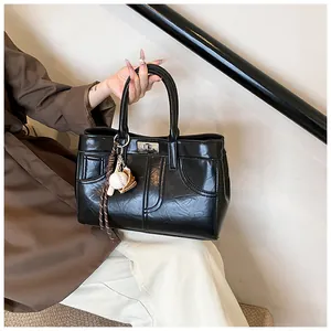 Detail of vintage brown tote bag with glossy wrinkled texture and baseball glove charm