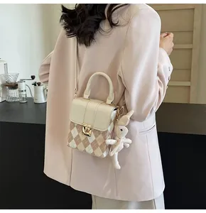 Detail of rhombic pattern bag with golden lock and cute knitted rabbit charm