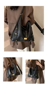 Detail of the soft leather texture and golden metal buckle on a black hobo tote bag
