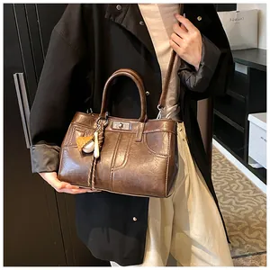 Detail of vintage brown crossbody bag with baseball charm and metallic twist lock