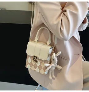 Detail view of rhombic pattern crossbody bag with a cute white knit rabbit pendant