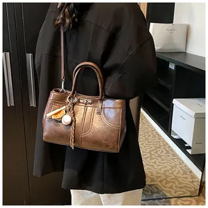 Detail view of vintage brown tote bag with glossy leather texture and baseball charm