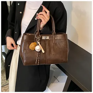 Detail of vintage brown PU leather tote bag with baseball charms and metal turn-lock