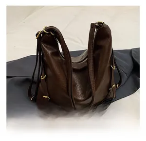 Close-up of brown litchi pattern leather tote with golden metal rings and adjustable straps