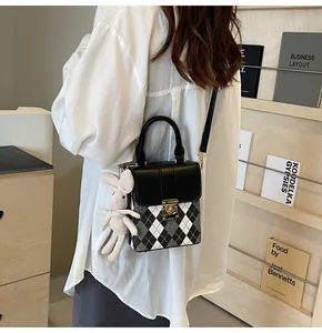 Detail of rhombic pattern crossbody bag with cute plush bunny pendant accessory