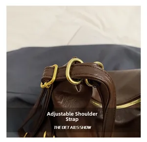 Detailed close-up of dark brown leather tote strap with matte gold adjustable buckle hardware