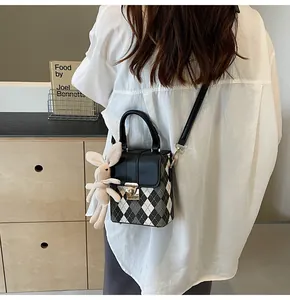 Detail of a plaid crossbody bag with a cute long-eared rabbit doll keychain