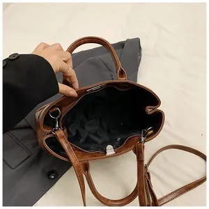Detail view of the vintage brown leather bag featuring silver hardware and black fabric lining