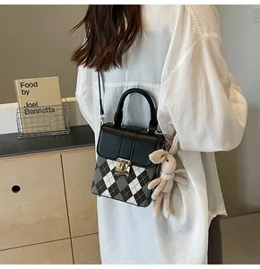 Detail of rhombic pattern bag with golden twist lock and knitted rabbit charm accessory