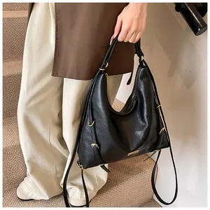 Detail of black pebbled leather hobo bag with golden hardware and adjustable strap