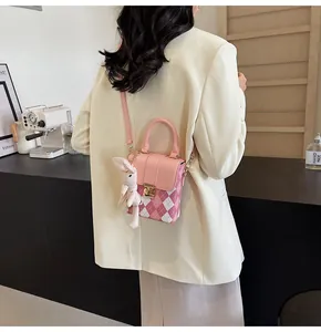 Back view of model wearing pink quilted crossbody bag with a cute white bunny charm