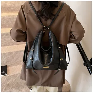 Rear view of a model wearing a large black matte leather hobo bag with gold hardware