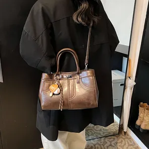 Vintage dark brown leather tote bag with crossbody strap and baseball charm