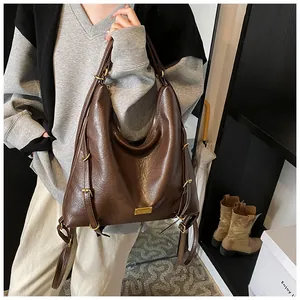 Detail of glossy brown leather tote bag with golden buckle and textured finish