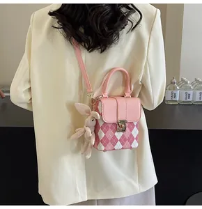 Detail of pink argyle quilted crossbody bag with cute plush rabbit charm accessory