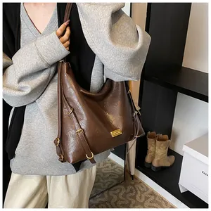 Detail of dark brown hobo tote bag featuring vintage pleated texture and gold metal buckles